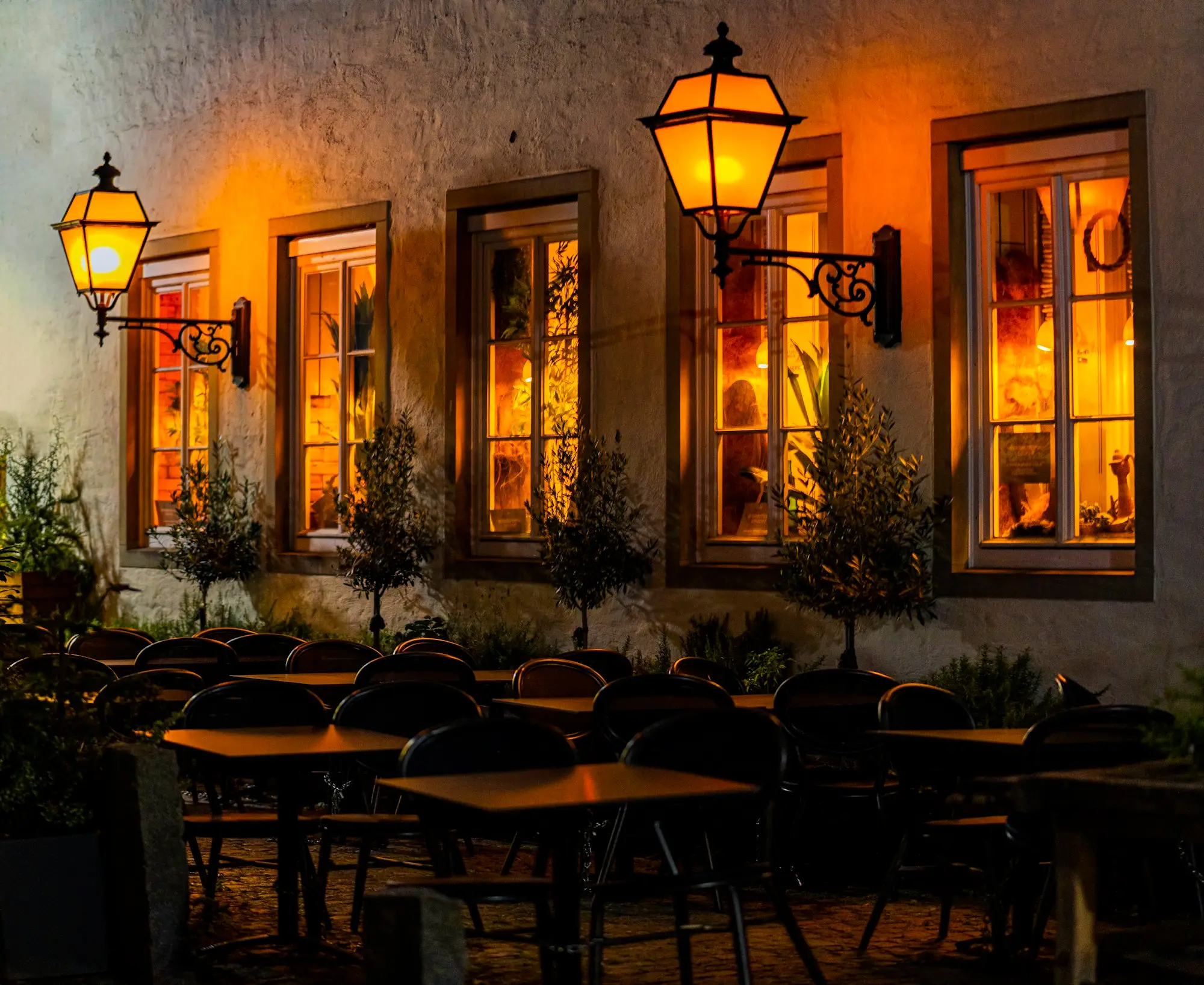 Café tables outside a lit shopfront