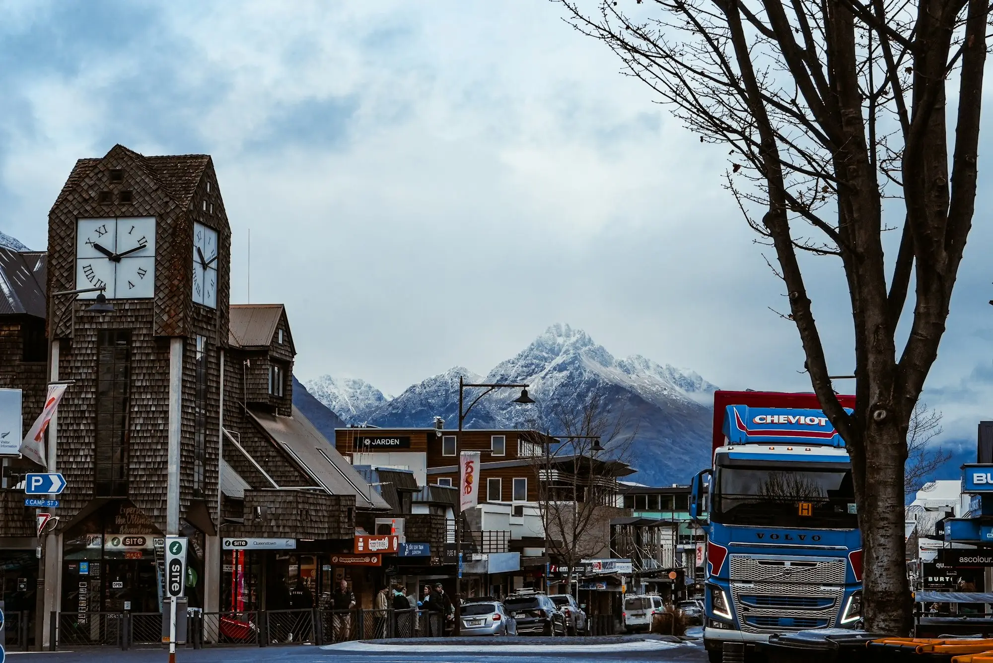 Stone clock tower in a town with snowy mountains